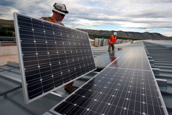 Montage einer Photovoltaikanlage durch zwei Höhenarbeiter auf einem Flachdach